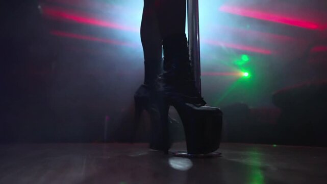 Pole dancer high heels on nightclub stage.