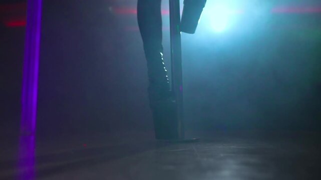 Pole dancer high heels on nightclub stage.