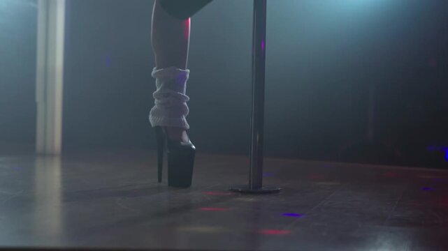 Pole dancer high heels on nightclub stage.