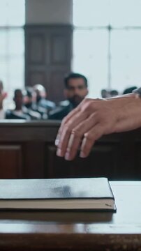 Vertical video: Placing judge in robe resting lifting right hand off book at court bench after oath