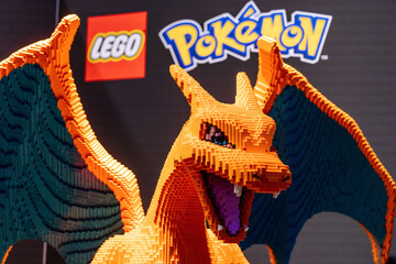 Fototapeta premium Cologne, Germany - August 26, 2026: LEGO Charizard sculpture displayed at gamescom, featuring vibrant orange and green colors, showcasing intricate brick details and iconic Pokemon branding