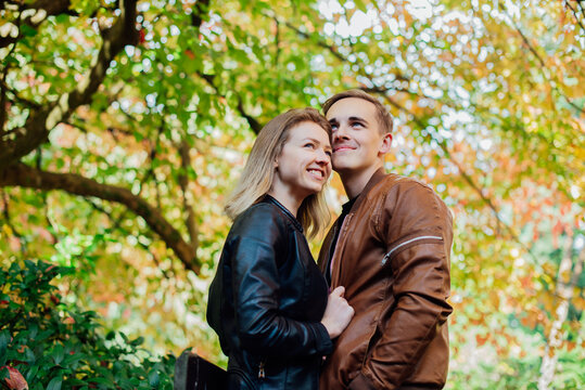 Portrait of young happy Caucasian couple in love hugging each other and enjoying the moment during romantic walk in nature in the fall park. Autumn mood. Youth feelings and first love concept