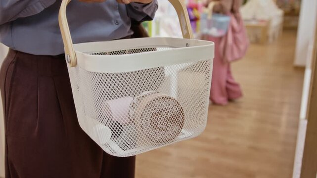 Unrecognizable woman placing cosmetic products inside shopping basket in retail boutique. Ideal for beauty market promotions, consumer behavior videos and commercial store advertising