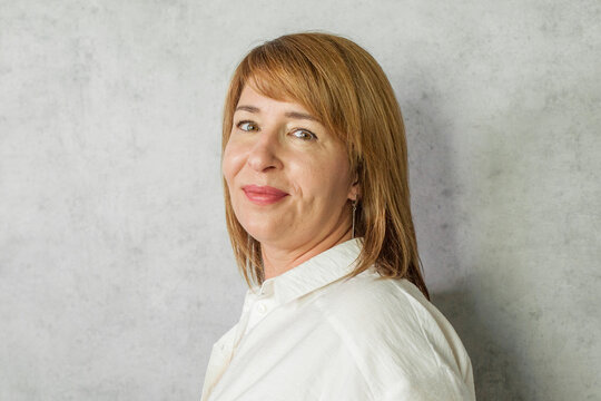 Attractive confident mature business woman standing on grey background