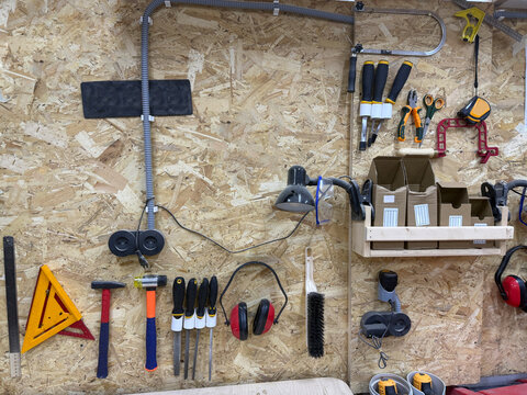 A workbench shows tools and materials on the wall and on the table