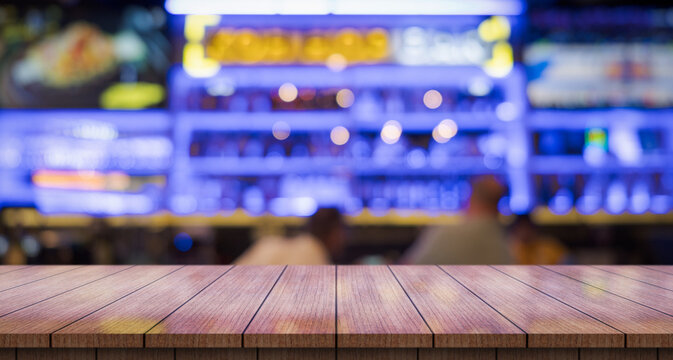 Empty wooden table top with lights bokeh on blur restaurant background.