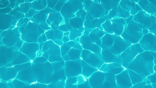 Bright blue swimming pool water with sunlight reflections, ripples and an abstract surface pattern. Natural summer background.