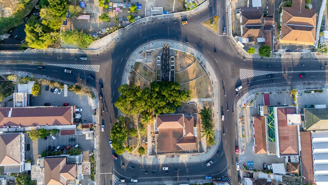 Aerial view of a roundabout featuring a central park with lush trees, surrounding roads with light traffic, and urban buildings in Boyolali, Central Java, Indonesia.