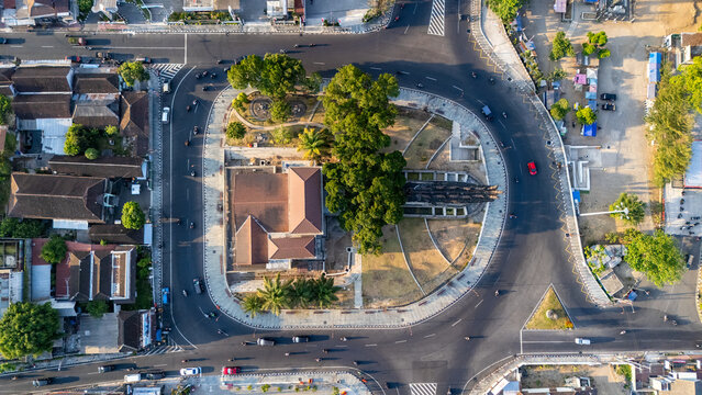 Aerial view of a roundabout featuring a central park with lush trees, a building, and surrounding roads with traffic in Boyolali, Central Java, Indonesia.