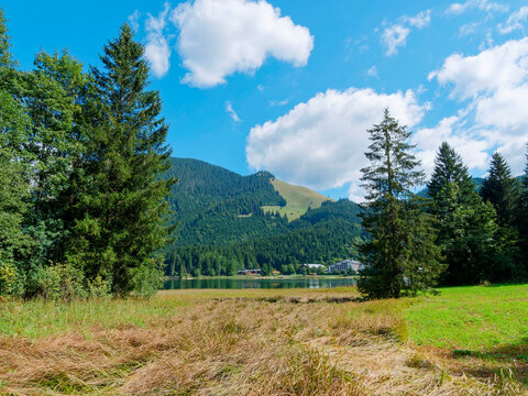 The village of Spitzingsee at the foot of the slopes, green meadows and forests of the Wilde Fraulein and Schwarzenkopf seen from the west shore of the lake