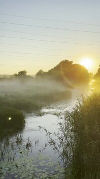 Sunrise emerges through mist over the Sula River creating a serene golden landscape with calm water and soft morning light in Poltava region, Ukraine
