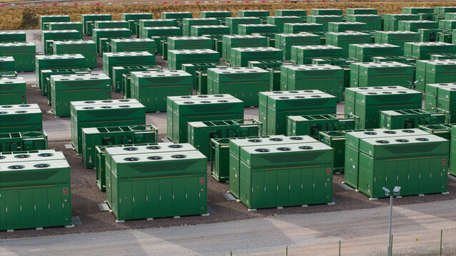 Aerial view of battery storage systems with rows of green containers in a large industrial facility in Birmingham, England, United Kingdom.