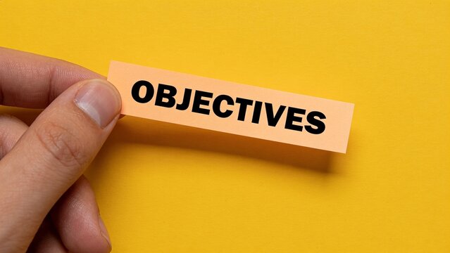 Hand holding objectives word on orange paper against yellow background