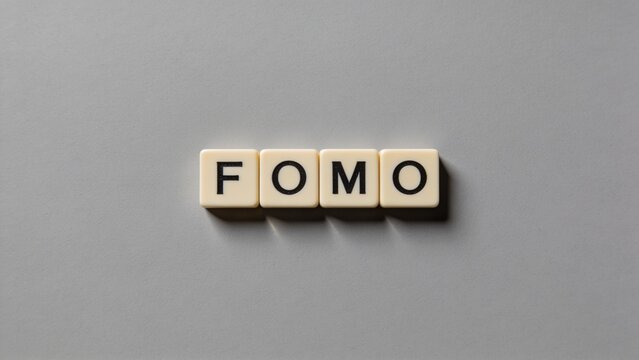 FOMO acronym spelled out with letter tiles on a neutral gray background