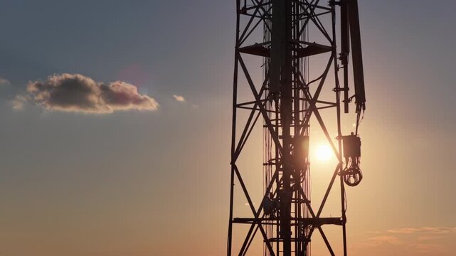 Cell tower silhouette against a sunset sky with a small cloud, representing global connectivity