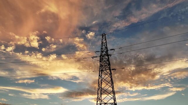 electric transmission tower silhouette against sunset sky