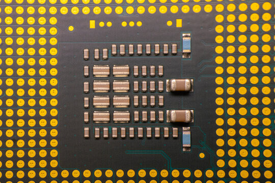 Close-up view of a computer microprocessor with intricate circuitry and gold pins on a black substrate, showcasing detailed electronic components and connections