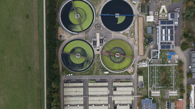 Aerial view of a wastewater treatment plant with circular sedimentation tanks and industrial buildings in Cologne, North Rhine-Westphalia, Germany.
