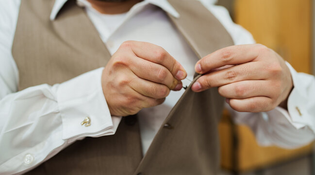 Hombre elegante ajustando la corbata con camisa blanca, chaleco y gemelos dorados