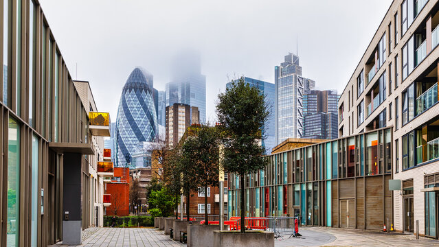 London financial district skyline featuring the iconic Gherkin building and other modern skyscrapers. Rising through the fog and illuminated at night