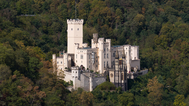 Aerial view of Stolzenfels Castle nestled in a dense forest, featuring its distinctive white towers, gothic architecture, and stone walls in Koblenz, Rheinland-Pfalz, Germany.
