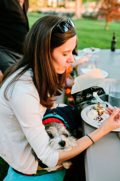 Woman Eating with Dog on Lap