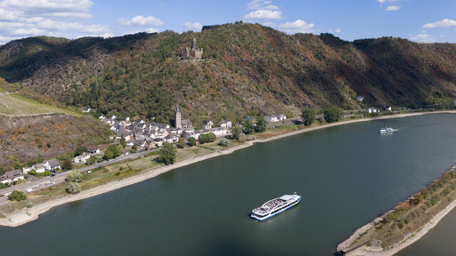 Aerial view of Burg Maus overlooking the town of Sankt Goarshausen and the Rhine River with a cruise ship sailing by under a clear blue sky in Sankt Goarshausen, Rhineland-Palatinate, Germany.