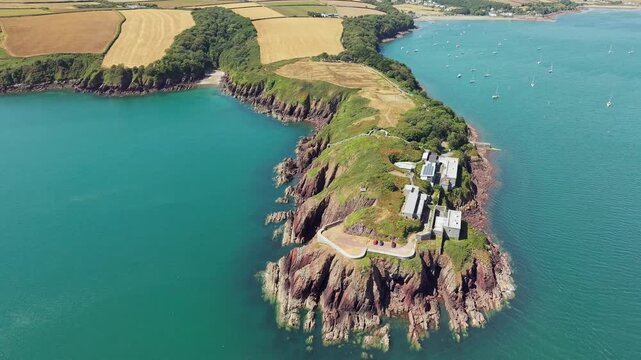 Dale Fort headland overlooking Milford Haven waterway, Victorian fortifications perched on cliffs beside calm bay filled with moored sailboats