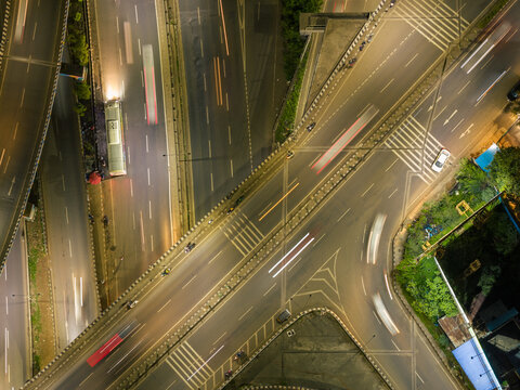 Aerial view of a highway interchange at night with light trails from moving vehicles and urban infrastructure in Pune, Maharashtra, India.