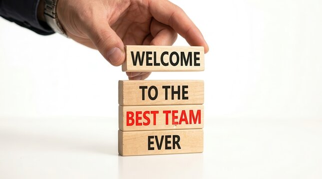 A businessman hand placing a wooden block to complete the phrase Welcome to the best team ever.