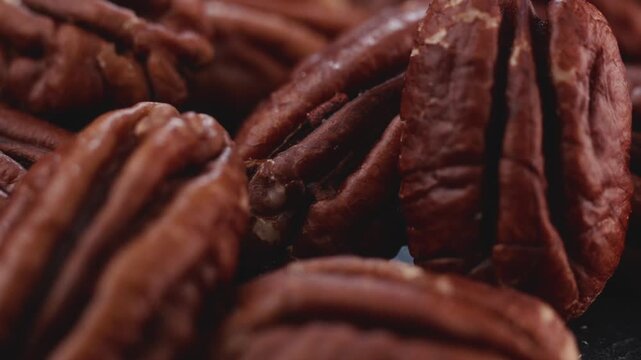 Extreme macro shot of fresh premium pecan nuts filling the frame with selective focus, rotating slowly with artistic lighting. Perfect for healthy eating, gourmet food, culinary, and dietary content.