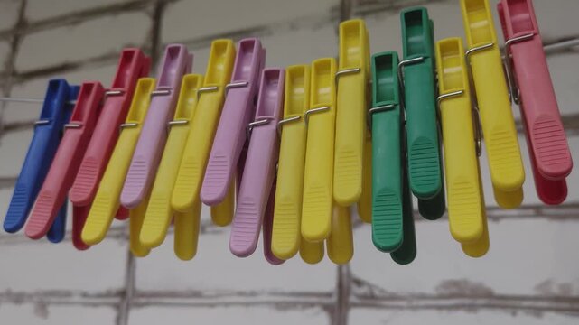 A bunch of clothes pegs hanging on a clothes line, ready for use