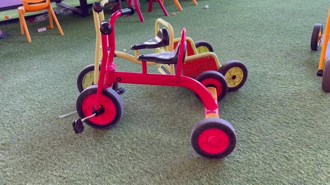Red children tricycle on artificial green turf