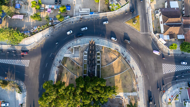 Aerial view of a roundabout intersection featuring a central monument, lush trees, and traffic moving along the asphalt roads in Boyolali, Central Java, Indonesia.