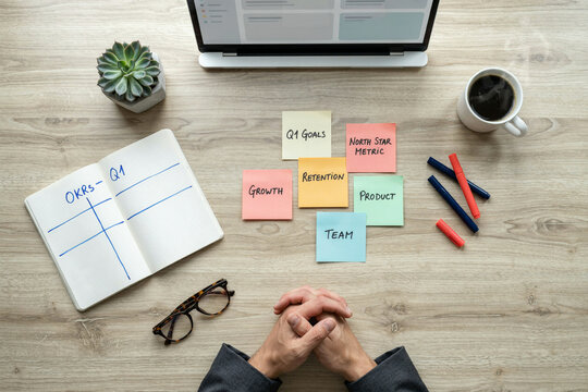 Business strategy planning with OKRs and sticky notes, corporate goal setting on wooden desk, professional workspace with laptop and notebook