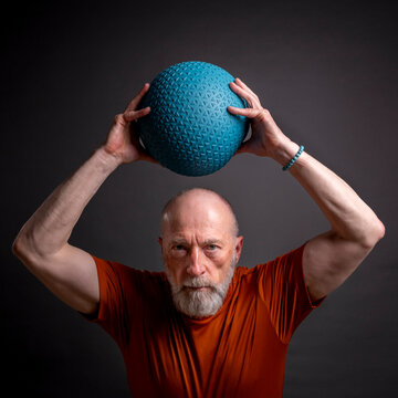 senior man (in late 60s) is exercising with a heavy slam or medicine  ball, activity and fitness over 60 concept