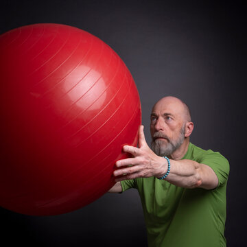 senior man is exercising with a large Swiss ball, activity and fitness over 60 concept