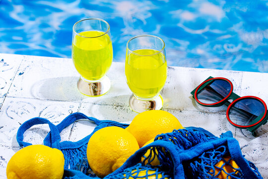 Two glasses of lemon liqueur, by the pool, on a sunny day, no people