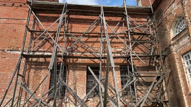 A brick church in the scaffolding: restoration of an ancient building under, closed up.