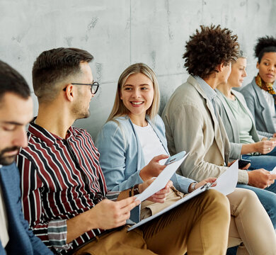 Group of young businss people sitting in chairs and waiting for an interview holding application documents