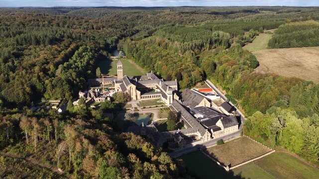 Aerial view of Orval Abbey surrounded by trees in Belgium during a sunny afternoon