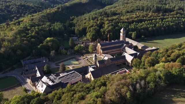 Aerial view of Orval Abbey nestled in the forest during a bright sunny afternoon
