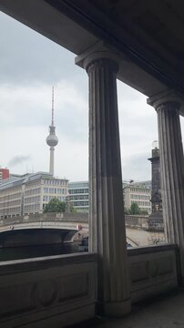 Beautiful Berlin cityscape with TV Tower, Friedrichs bridge over Spree river, touristic ship sailing under the river and giant columns near Old National gallery in typical moody rainy weather.