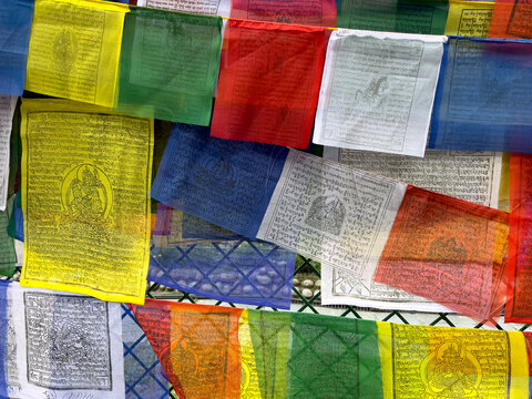 Close-up texture of colorful Tibetan Buddhist prayer flags with printed mantras and sacred deities in Kathmandu, Nepal