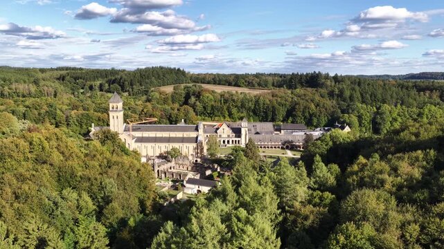 Aerial view of Orval Abbey surrounded by green summer forest during daylight