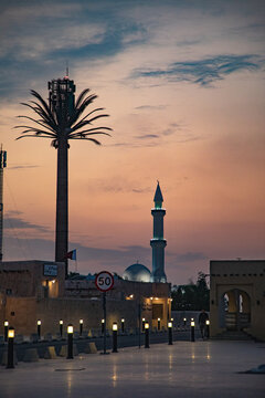 View of a mosque minaret and a palm-shaped cell tower at sunset in the historic district of Doha, Doha Municipality, Qatar.