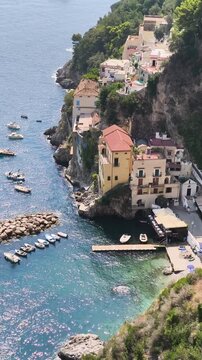 Vertical view of Marina di Conca fishing village nestled in the cliffs with colorful houses and small harbor, Conca dei Marini, Amalfi Coast, Italy.