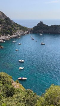 Vertical view of Conca dei Marini bay with anchored boats and Capo di Conca watchtower on the cliff, Amalfi Coast, Italy.