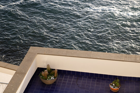 View of a balcony with blue tiles and potted cacti overlooking the sea in Ischia, Campania, Italy.