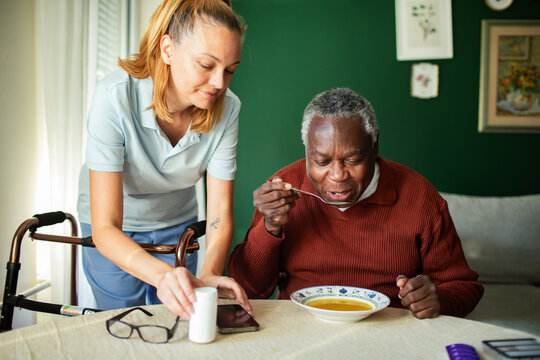 Caregiver assisting senior man eating soup at home